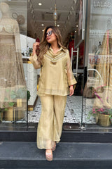 Woman in a beige outfit standing in front of a store window display.
