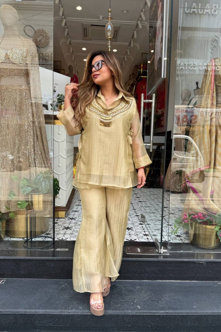 Woman in a beige outfit standing in front of a store window display.