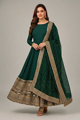 Woman wearing a green traditional outfit with gold embroidery on a gray background