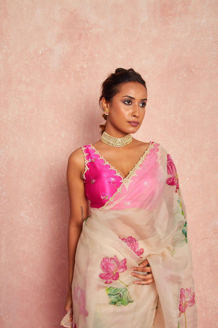 Woman wearing a pink blouse and floral saree against a pink background