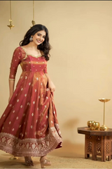 Woman wearing a traditional maroon anarkali suit with gold embroidery against a beige background.