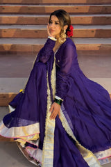 Woman in a traditional purple outfit with gold details sitting on steps.