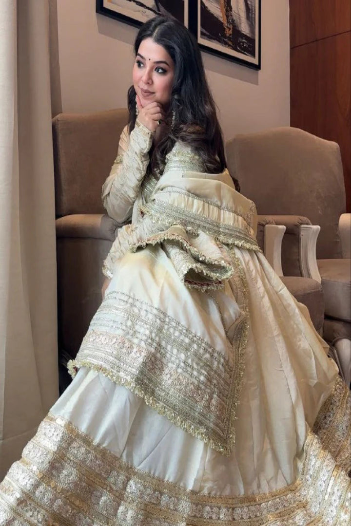 Woman in a traditional embroidered outfit sitting indoors.