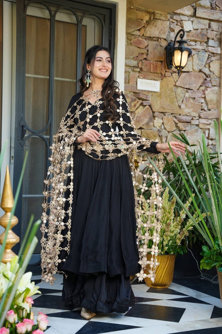 Woman in traditional outfit standing in front of a stone wall with decorative lights.
