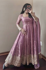 Person wearing a pink anarkali suit with gold embroidery in a room.