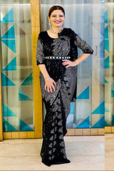 Woman in a black and white patterned outfit standing in front of a geometrically patterned wall.