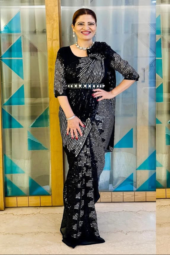 Woman in a black and white patterned outfit standing in front of a geometrically patterned wall.