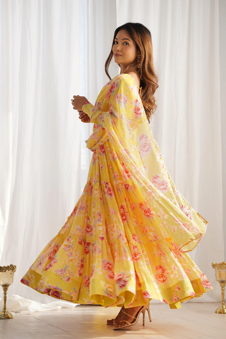 Woman wearing a yellow floral dress against a white curtain background