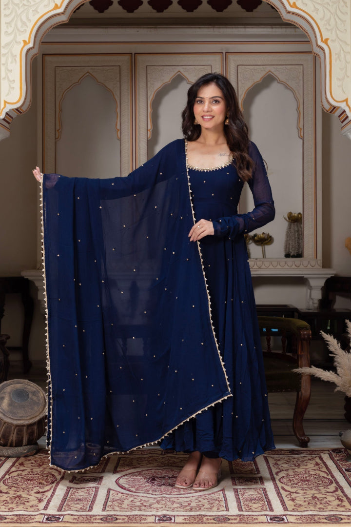 Woman in a blue traditional outfit with a matching dupatta in an ornate room.
