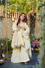 Woman in a traditional outfit standing outdoors with decorative elements and plants.
