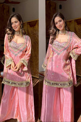 Woman wearing a pink traditional outfit with gold detailing indoors.