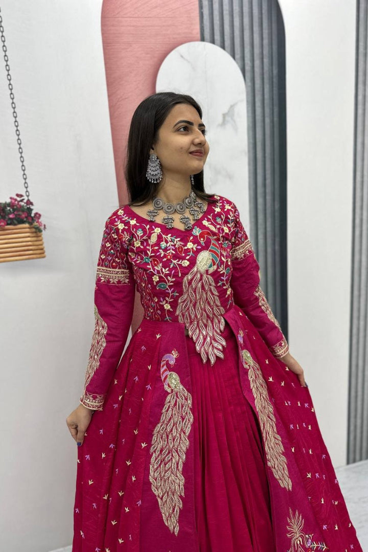 Woman wearing a pink embroidered traditional outfit in a minimal indoor setting.