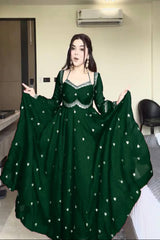 Woman wearing a green dress with white embellishments in an indoor setting.