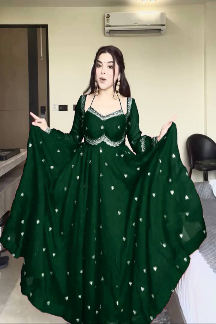 Woman wearing a green dress with white embellishments in an indoor setting.