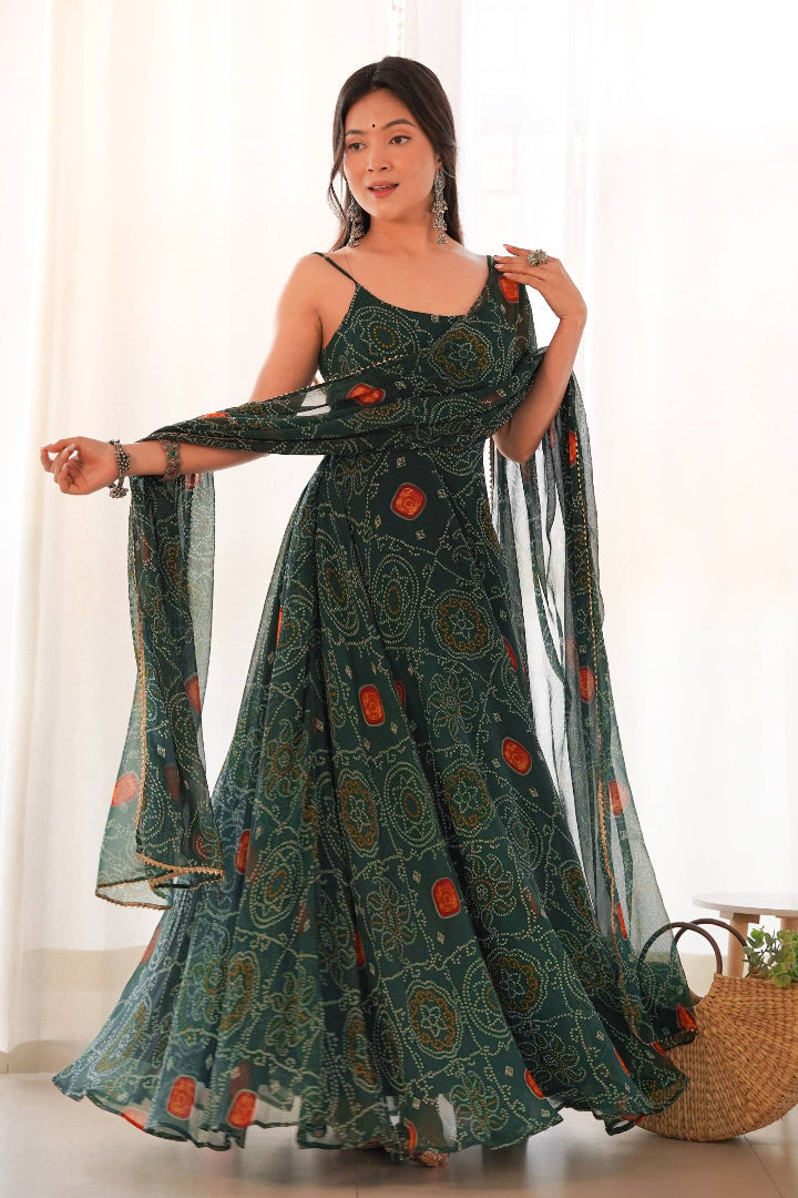 Woman wearing a long, patterned dress with a sheer dupatta, standing indoors.