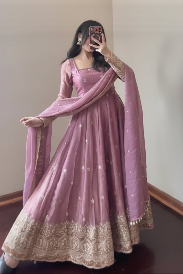 Person wearing a pink traditional outfit with gold details, holding a matching dupatta.