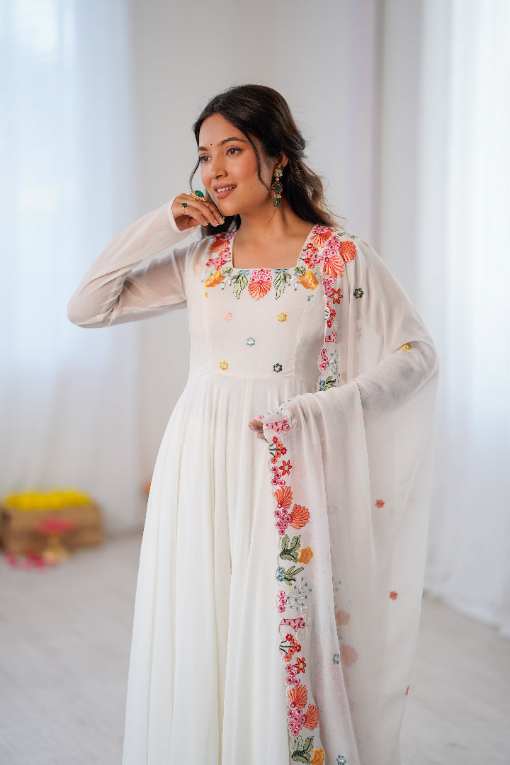 A woman wearing a long white embroidered dress 